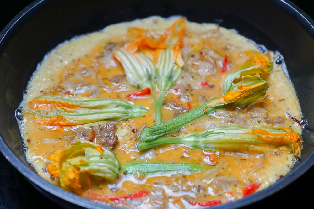 Omelette mit Zucchiniblüten und Fette Henne in der Pfanne